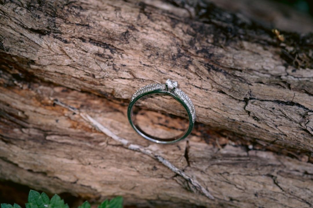 En elegant diamantring i silver placerad på en rustik trädstam.